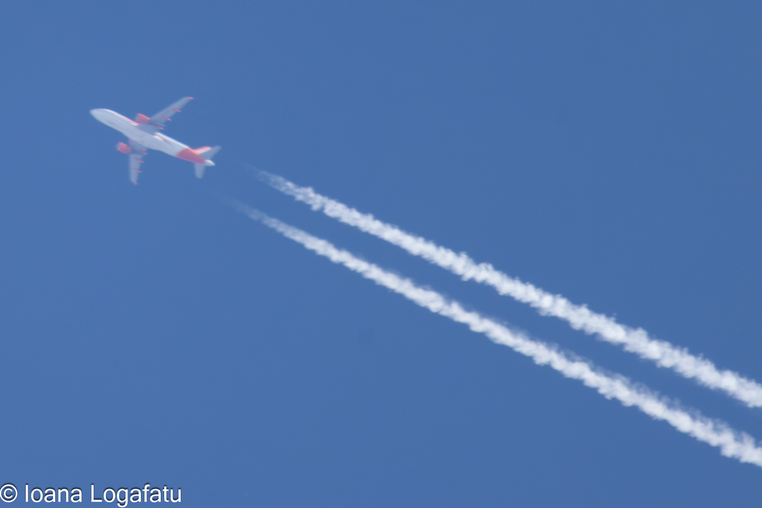 Jet soaring through a clear blue sky leaves trails